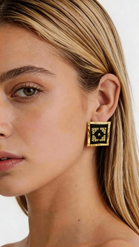 Ξεχωρίστε με αυτά τα εντυπωσιακά statement κεντητά σκουλαρίκια που συνδυάζουν την παραδοσιακή ελληνική τέχνη του κεντήματος με σύγχρονο γεωμετρικό design. Σχεδιασμένα από την Ελληνίδα Σχεδιάστρια Κοσμημάτων Αικατερίνη Χαλκιαδάκη, αυτά τα μοναδικά χειροποίητα σκουλαρίκια φέρουν έναν πλούσιο χρυσόκλωστο κεντητό σχεδιασμό πάνω σε κομψό μαύρο φόντο. Κάθε σκουλαρίκι αποτελεί ένα μικρό έργο τέχνης με περίπλοκα γεωμετρικά μοτίβα που δημιουργούν μια εκπληκτική οπτική αίσθηση. Η χρυσή κλωστή λάμπει υπέροχα πάνω στη μαύρη βάση, προσφέροντας έναν εντυπωσιακό συνδυασμό που ταιριάζει τόσο σε καθημερινές όσο και σε επίσημες εμφανίσεις. Αυτά τα μοντέρνα κρεμαστά σκουλαρίκια είναι ιδανικά για γυναίκες που αγαπούν τα πρωτότυπα κοσμήματα με ελληνικό χαρακτήρα. Το τετράγωνο σχήμα τους προσφέρει μια σύγχρονη αισθητική, ενώ η κεντητή λεπτομέρεια φέρνει την παράδοση στο προσκήνιο. Υλικό: Ορείχαλκος, Ύφασμα Φροντίστε τα σκουλαρίκια σας αποθηκεύοντάς τα σε στεγνό μέρος και αποφεύγοντας την επαφή με υγρασία και χημικά προϊόντα.