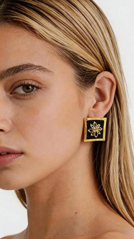 Τα εντυπωσιακά statement σκουλαρίκια με κεντητά γεωμετρικά σχέδια σε μαύρο φόντο θα γίνουν το επίκεντρο κάθε σας εμφάνισης. Αυτά τα μοναδικά χειροποίητα σκουλαρίκια, σχεδιασμένα από την Ελληνίδα Σχεδιάστρια Κοσμημάτων Αικατερίνη Χαλκιαδάκη, συνδυάζουν την παραδοσιακή τεχνική του κεντήματος με χρυσοκλωστή και τη σύγχρονη αισθητική. Κάθε σκουλαρίκι φέρει περίτεχνα κεντητά γεωμετρικά μοτίβα που ξεχωρίζουν πάνω στο βαθύ μαύρο φόντο, δημιουργώντας μια εκπληκτική αντίθεση που τραβάει όλα τα βλέμματα. Η χρυσοκλωστή προσθέτει μια πολυτελή λάμψη, ενώ ο τετράγωνος σχεδιασμός τους τα καθιστά ιδανικά για μοντέρνες γυναίκες που αγαπούν να ξεχωρίζουν. Αυτά τα εντυπωσιακά κρεμαστά σκουλαρίκια είναι τέλεια για ειδικές περιστάσεις, γάμους ή βραδινές εξόδους, αλλά μπορούν εξίσου εύκολα να αναβαθμίσουν και ένα καθημερινό ντύσιμο. Η ελληνική χειροτεχνία τους εγγυάται την ποιότητα και τη μοναδικότητά τους. Υλικό: Ορείχαλκος, Ύφασμα Φροντίστε τα απαλά με μαλακό πανί και αποφύγετε την επαφή με νερό και αρώματα για να διατηρήσουν τη λάμψη τους.