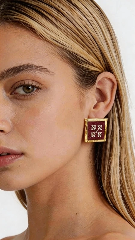 Κεντητά σκουλαρίκια statement με γεωμετρικά σχέδια από χρυσοκλωστή σε μπορντό - SKOUL-4717 | Candiashop Boutique, Τα statement κεντητά σκουλαρίκια με γεωμετρικά σχέδια από χρυσοκλωστή σε υπέροχο μπορντό χρώμα προσδίδουν μια μοναδική πινελιά κομψότητας σε κάθε σας εμφάνιση. Σχεδιασμένα από την Ελληνίδα Σχεδιάστρια Κοσμημάτων Αικατερίνη Χαλκιαδάκη, αυτά τα εντυπωσιακά χειροποίητα σκουλαρίκια συνδυάζουν την παραδοσιακή τέχνη του κεντήματος με σύγχρονο design. Κάθε σκουλαρίκι δημιουργείται με ιδιαίτερη προσοχή στη λεπτομέρεια, χρησιμοποιώντας χρυσοκλωστή που σχηματίζει γεωμετρικά μοτίβα σε βαθύ μπορντό φόντο. Η τετραγωνική φόρμα με χρυσό περίγραμμα προσφέρει μια σύγχρονη ερμηνεία του κλασικού κεντήματος, ιδανικά για γυναίκες που αγαπούν τα statement κοσμήματα. Αυτά τα μοναδικά σκουλαρίκια είναι τέλεια για ιδιαίτερες στιγμές όπως γάμους, βραδινές εξόδους ή επαγγελματικά events. Συνδυάζονται υπέροχα με μονόχρωμα outfits, προσδίδοντας χρώμα και κομψότητα. Υλικό: Ορείχαλκος, Ύφασμα Φροντίδα: Φυλάσσετε σε στεγνό μέρος και αποφεύγετε την επαφή με νερό και χημικά προϊόντα για τη διατήρηση των χρωμάτων.