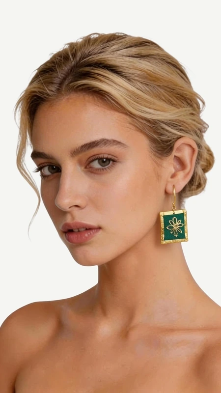 Τα εντυπωσιακά κεντητά σκουλαρίκια statement σε πράσινο χρώμα προσφέρουν μια μοναδική αισθητική που συνδυάζει την παραδοσιακή τέχνη του κεντήματος με σύγχρονο γεωμετρικό σχεδιασμό. Κάθε κομμάτι, σχεδιασμένο από την Ελληνίδα Σχεδιάστρια Κοσμημάτων Αικατερίνη Χαλκιαδάκη, αποτελεί έργο τέχνης που μετατρέπει κάθε εμφάνιση σε ξεχωριστή. Η χρυσοκλωστή που χρησιμοποιείται δημιουργεί εκθαμβωτικές αντανακλάσεις φωτός, ενώ το έντονο πράσινο χρώμα προσθέτει φρεσκάδα και ζωντάνια. Τα τετράγωνα κεντητά στοιχεία με το κεντρικό γεωμετρικό μοτίβο σε χρυσές αποχρώσεις δημιουργούν μια εκλεπτυσμένη αντίθεση που τραβά τα βλέμματα. Ιδανικά για ιδιαίτερες στιγμές και εκδηλώσεις, αυτά τα χειροποίητα σκουλαρίκια συμπληρώνουν τέλεια τόσο κλασικά όσο και μοντέρνα σύνολα. Η άνετη εφαρμογή και το ελαφρύ βάρος τα καθιστούν κατάλληλα για όλη τη μέρα. Υλικό: Ορείχαλκος, Ύφασμα Για τη διατήρηση της ομορφιάς τους, φυλάξτε τα σε στεγνό μέρος μακριά από άμεσο ήλιο.