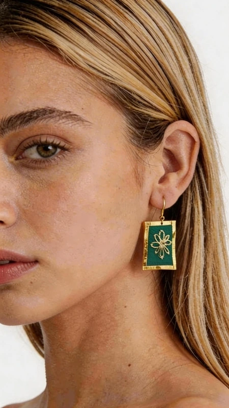 Κεντητά σκουλαρίκια statement με γεωμετρικά σχέδια από χρυσοκλωστή σε πράσινο - SKOUL-4712 | Candiashop Boutique, Τα εντυπωσιακά κεντητά σκουλαρίκια statement σε πράσινο χρώμα προσφέρουν μια μοναδική αισθητική που συνδυάζει την παραδοσιακή τέχνη του κεντήματος με σύγχρονο γεωμετρικό σχεδιασμό. Κάθε κομμάτι, σχεδιασμένο από την Ελληνίδα Σχεδιάστρια Κοσμημάτων Αικατερίνη Χαλκιαδάκη, αποτελεί έργο τέχνης που μετατρέπει κάθε εμφάνιση σε ξεχωριστή. Η χρυσοκλωστή που χρησιμοποιείται δημιουργεί εκθαμβωτικές αντανακλάσεις φωτός, ενώ το έντονο πράσινο χρώμα προσθέτει φρεσκάδα και ζωντάνια. Τα τετράγωνα κεντητά στοιχεία με το κεντρικό γεωμετρικό μοτίβο σε χρυσές αποχρώσεις δημιουργούν μια εκλεπτυσμένη αντίθεση που τραβά τα βλέμματα. Ιδανικά για ιδιαίτερες στιγμές και εκδηλώσεις, αυτά τα χειροποίητα σκουλαρίκια συμπληρώνουν τέλεια τόσο κλασικά όσο και μοντέρνα σύνολα. Η άνετη εφαρμογή και το ελαφρύ βάρος τα καθιστούν κατάλληλα για όλη τη μέρα. Υλικό: Ορείχαλκος, Ύφασμα Για τη διατήρηση της ομορφιάς τους, φυλάξτε τα σε στεγνό μέρος μακριά από άμεσο ήλιο.