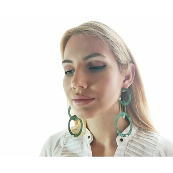 Μεγάλα εντυπωσιακά σκουλαρίκια μακριά καρφωτά με μαργαριτάρια - 3731, Ανακαλύψτε τη μαγεία των μεγάλων εντυπωσιακών σκουλαρικιών που συνδυάζουν την κομψότητα του χαλκού με την πράσινη πατίνα σε ένα μοναδικό design. Αυτά τα χειροποίητα μακριά καρφωτά σκουλαρίκια, σχεδιασμένα από την Ελληνίδα Σχεδιάστρια Κοσμημάτων Αικατερίνη Χαλκιαδάκη, δημιουργούν statement look που προσελκύει τα βλέμματα.
Το innovative design με τους αλληλένδετους κρίκους σε πράσινη πατίνα δίνει bohemian αισθητική που ταιριάζει τέλεια σε σύγχρονες γυναίκες. Κάθε κρίκος είναι χειροτεχνημένος από υψηλής ποιότητας χαλκό και διακοσμημένος με φυσικά μαργαριτάρια που προσθέτουν λάμψη και κομψότητα. Η μοναδική πράσινη πατίνα δημιουργεί vintage αίσθηση που συνδυάζεται άψογα με μοντέρνα και κλασικά outfits.
Τα κρεμαστά σκουλαρίκια αυτά είναι ιδανικά για ιδιαίτερες στιγμές, νυφικές εμφανίσεις ή everyday chic looks. Η ελληνική τεχνογνωσία φαίνεται σε κάθε λεπτομέρεια, από την τέλεια ισορροπία των κρίκων μέχρι την προσεκτική τοποθέτηση των περλών. Φυλάξτε τα σε στεγνό μέρος και καθαρίστε τα απαλά με μαλακό πανί.