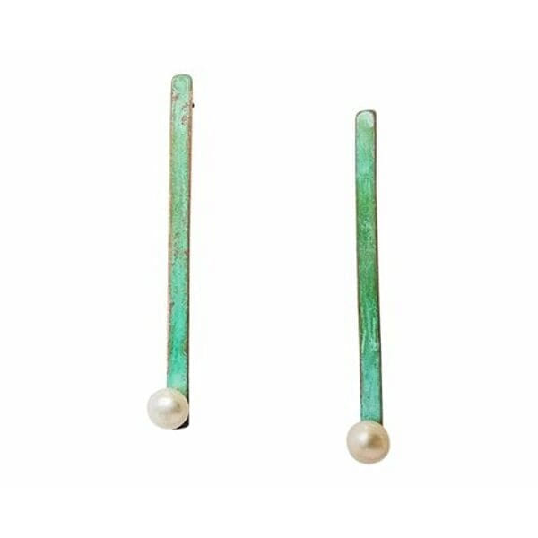 Ανακαλύψτε τη μοναδική ομορφιά των μακριών καρφωτών σκουλαρικιών με μαργαριτάρια και πράσινη πατίνα, που συνδυάζουν τη σύγχρονη αισθητική με την παραδοσιακή χειροτεχνία. Σχεδιασμένα από την Ελληνίδα Σχεδιάστρια Κοσμημάτων Αικατερίνη Χαλκιαδάκη, αυτά τα εντυπωσιακά σκουλαρίκια αποτελούν την τέλεια επιλογή για γυναίκες που αναζητούν πρωτότυπα και κομψά κοσμήματα.\u000AΚάθε σκουλαρίκι είναι χειροποίητο από χαλκό υψηλής ποιότητας με μοναδική πράσινη πατίνα που δημιουργεί ένα vintage αποτέλεσμα γεμάτο χαρακτήρα. Οι φυσικές πέρλες στο κάτω μέρος προσθέτουν κλασική κομψότητα και απαλότητα, δημιουργώντας έναν τέλειο συνδυασμό μοντέρνων και παραδοσιακών στοιχείων. Η μακριά γραμμική σιλουέτα επιμηκύνει τον λαιμό και προσδίδει μια καθαρή, σύγχρονη αισθητική.
