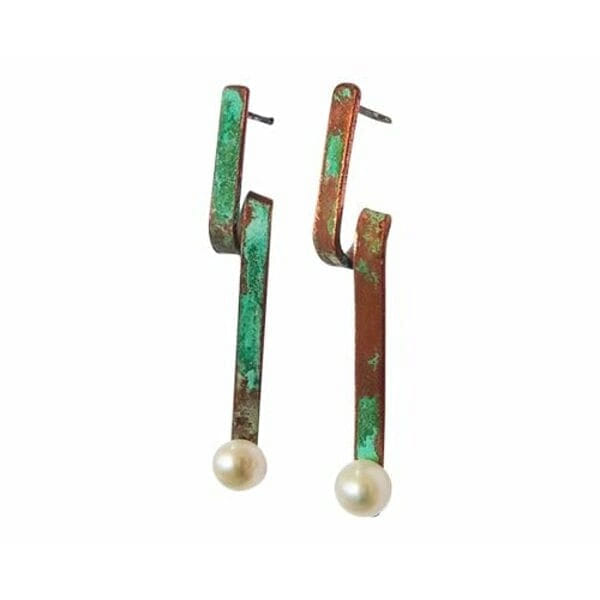 Αυτά τα εντυπωσιακά χειροποίητα σκουλαρίκια καρφωτά με μαργαριτάρια συνδυάζουν την κλασική κομψότητα με τη σύγχρονη αισθητική. Σχεδιασμένα από την Ελληνίδα Σχεδιάστρια Κοσμημάτων Αικατερίνη Χαλκιαδάκη, αποτελούν έναν ιδανικό συνδυασμό τέχνης και στυλ που ανανεώνει κάθε εμφάνιση.\u000AΗ μοναδική geometric σιλουέτα με την πράσινη πατίνα δημιουργεί μια vintage αισθητική που ξεχωρίζει, ενώ οι λευκές πέρλες στο κάτω μέρος προσδίδουν κλασική χάρη. Ο χαλκός έχει υποστεί ειδική επεξεργασία που δημιουργεί τον χαρακτηριστικό πράσινο χρωματισμό, δίνοντας σε κάθε κόσμημα μια ξεχωριστή προσωπικότητα.\u000AΑυτά τα κρεμαστά σκουλαρίκια είναι ιδανικά για γυναίκες που αγαπούν τα statement κοσμήματα με χαρακτήρα. Η εργονομική τους σχεδίαση εξασφαλίζει άνεση καθ\u0027 όλη τη διάρκεια της ημέρας, ενώ η ποιότητα κατασκευής εγγυάται αντοχή και διάρκεια.