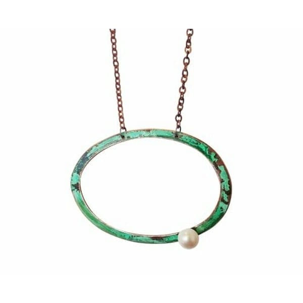 Ανακαλύψτε την τέλεια ισορροπία μεταξύ σύγχρονου design και κλασικής κομψότητας με αυτό το μεγάλο γυναικείο κολιέ με μαργαριτάρι. Σχεδιασμένο από την Ελληνίδα Σχεδιάστρια Κοσμημάτων Αικατερίνη Χαλκιαδάκη, αυτό το χειροποίητο κόσμημα συνδυάζει την ομορφιά του οξειδωμένου χαλκού με την κομψότητα της φρέσκιας πέρλας.\u000AΤο γεωμετρικό σχήμα του κύκλου δημιουργεί ένα statement look που προσελκύει τα βλέμματα, ενώ οι αποχρώσεις του πράσινου χαλκού προσδίδουν έναν μοναδικό vintage χαρακτήρα. Η λευκή πέρλα στη βάση του κολιέ προσφέρει την τέλεια αντίθεση, δημιουργώντας ένα εντυπωσιακό αποτέλεσμα που συνδυάζεται εύκολα με κάθε outfit.\u000AΙδανικό για τις γυναίκες που αγαπούν τα μεγάλα εντυπωσιακά κολιέ και αναζητούν κοσμήματα με προσωπικότητα. Φοριέται εξίσου όμορφα με casual ή πιο επίσημα looks, προσφέροντας άπειρες δυνατότητες styling. Αποθηκεύετε σε στεγνό μέρος και καθαρίζετε απαλά με μαλακό πανί για να διατηρήσετε τη φυσική οξείδωση του χαλκού.