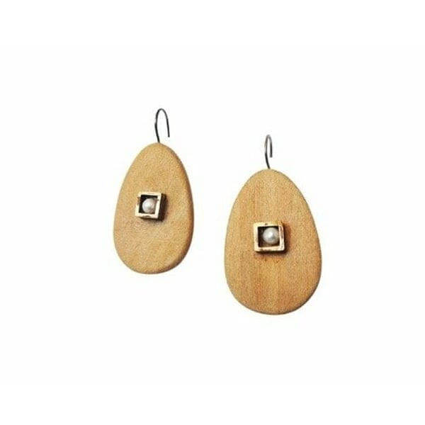 Σκουλαρίκια κρεμαστά με ξύλο και μαργαριτάρια - 3983, Ανακαλύψτε τη φυσική κομψότητα με αυτά τα μοναδικά κρεμαστά σκουλαρίκια που συνδυάζουν ξύλο και μαργαριτάρια σε έναν υπέροχο σχεδιασμό. Σχεδιασμένα από την Ελληνίδα Σχεδιάστρια Κοσμημάτων Αικατερίνη Χαλκιαδάκη, αυτά τα χειροποίητα κοσμήματα προσφέρουν μια σύγχρονη ματιά στην κλασική κομψότητα.
Κάθε σκουλαρίκι χαρακτηρίζεται από μια οβάλ ξύλινη βάση σε φυσικό καφέ χρώμα που συμπληρώνεται από ένα τετράγωνο μεταλλικό στοιχείο με λευκή πέρλα στο κέντρο. Ο συνδυασμός αυτός δημιουργεί μια υπέροχη αντίθεση υφών και χρωμάτων που προσελκύει το βλέμμα. Η φυσική ζεστασιά του ξύλου αρμονίζει τέλεια με τη λάμψη των μαργαριταριών, δημιουργώντας ένα κόσμημα που είναι ιδανικό τόσο για καθημερινή όσο και για ειδική εμφάνιση.