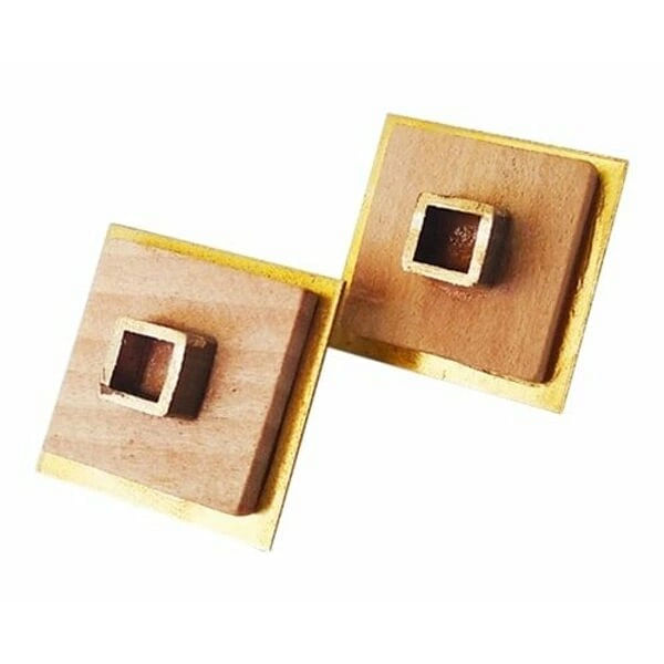 Ανακαλύψτε τη μοναδική ομορφιά των χειροποίητων καρφωτών σκουλαρικιών με ξύλο, που συνδυάζουν τη φυσική θερμότητα του ξύλου με τη χρυσαφί λάμψη του ορείχαλκου. Αυτά τα εντυπωσιακά τετράγωνα σκουλαρίκια είναι σχεδιασμένα από την Ελληνίδα Σχεδιάστρια Κοσμημάτων Αικατερίνη Χαλκιαδάκη και αποτελούν την τέλεια επιλογή για τη σύγχρονη γυναίκα που αναζητά μοντέρνα κοσμήματα με χαρακτήρα.\u000AΗ γεωμετρική τους φόρμα και ο μινιμαλιστικός σχεδιασμός τα καθιστούν ιδανικά για καθημερινή χρήση, ενώ παράλληλα προσδίδουν μια εκλεπτυσμένη πινελιά σε κάθε εμφάνιση. Το συνδυασμός των φυσικών υλικών δημιουργεί μια αίσθηση οργανικής κομψότητας που ταιριάζει τόσο σε casual όσο και σε πιο επίσημα looks. Αυτά τα πρωτότυπα γυναικεία σκουλαρίκια αποτελούν μια εξαιρετική επένδυση για τη συλλογή κοσμημάτων σας. Συνδυάστε τα με άλλα κομμάτια από την ίδια σειρά για ένα ολοκληρωμένο boho chic στυλ. Για τη διατήρηση τους, αποφεύγετε την επαφή με νερό και αποθηκεύετε τα σε στεγνό μέρος.