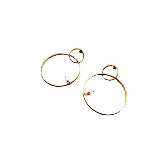 Τα εντυπωσιακά μεγάλα σκουλαρίκια κρίκοι με πέρλες αποτελούν την τέλεια επιλογή για τη γυναίκα που αναζητά statement κοσμήματα με σύγχρονη αισθητική. Σχεδιασμένα από την Ελληνίδα Σχεδιάστρια Κοσμημάτων Αικατερίνη Χαλκιαδάκη, αυτά τα χειροποίητα σκουλαρίκια συνδυάζουν τη χρυσή λάμψη του ορείχαλκου με την κομψότητα των πραγματικών πεταλούδων.\u000AΗ μοναδική σύνθεση διπλών κρίκων δημιουργεί ένα γεωμετρικό παιχνίδι που προσελκύει το βλέμμα, ενώ οι λευκές πέρλες προσθέτουν μια νότα κλασικής κομψότητας. Το καρφωτό κλείσιμο εξασφαλίζει άνετη και ασφαλή χρήση, καθιστώντας τα ιδανικά για όλη την ημέρα.\u000AΑυτά τα μοντέρνα κρεμαστά σκουλαρίκια είναι ιδανικά για ειδικές περιστάσεις όπως γάμους, cocktail parties ή επαγγελματικά events. Συνδυάζονται τέλεια με μονόχρωμα outfits και προσδίδουν στο look σας μια σύγχρονη boho αισθητική.