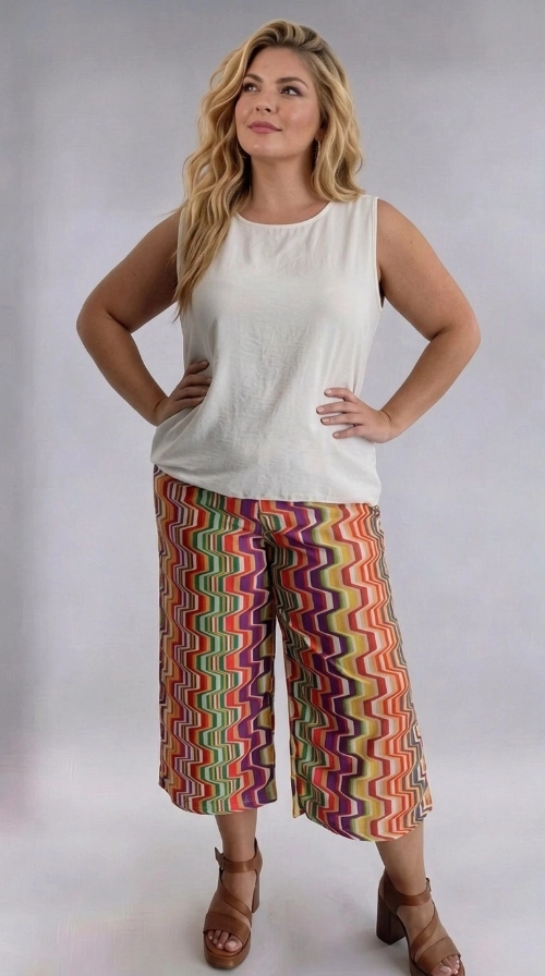 Γυναικεία ζιπ κιλότ καλοκαιρινή εμπριμέ plus size - ZIP111 | Candiashop Boutique, Ανακαλύψτε τη μοναδική αυτή γυναικεία ζιπ κιλότ plus size που θα αναβαθμίσει άμεσα τη γκαρνταρόμπα σας με έναν εκρηκτικό συνδυασμό χρωμάτων και στυλ. Το εντυπωσιακό ζιγκ-ζαγκ μοτίβο της συνδυάζει αποχρώσεις πορτοκαλί, μωβ, πράσινου, κίτρινου, κόκκινου και λευκού, δημιουργώντας ένα ζωντανό και παιχνιδιάρικο αποτέλεσμα που τραβά αμέσως τα βλέμματα. Η φαρδιά γραμμή της κιλότ εξασφαλίζει άνετη εφαρμογή, ενώ το μήκος κάτω από το γόνατο τη καθιστά ιδανική για κάθε σωματότυπο. Το ρετρό-εμπνευσμένο σχέδιό της αποπνέει καλοκαιρινή διάθεση και ελευθερία. Μπορεί να φορεθεί με ένα απλό λευκό αμάνικο τοπ, όπως στην εικόνα, για ένα ισορροπημένο και κομψό σύνολο. Συνδυάστε την με πλατφόρμες ή εσπαντρίγιες για μια boho-chic εμφάνιση. Ιδανική για καλοκαιρινές εξόδους, διακοπές, αλλά και χαλαρές καθημερινές εμφανίσεις, αυτή η κιλότ είναι το must-have κομμάτι της σεζόν για κάθε γυναίκα που αγαπά το στυλ και την άνεση.