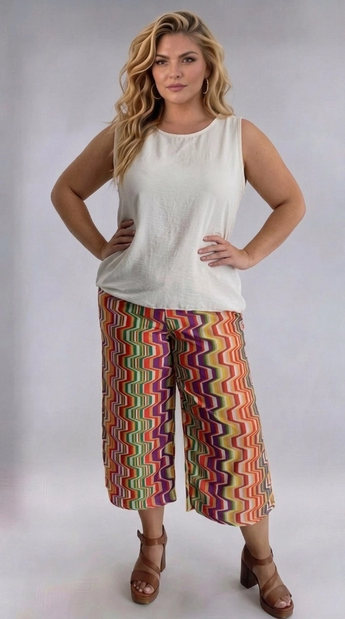 Γυναικεία ζιπ κιλότ καλοκαιρινή εμπριμέ plus size - ZIP111 | Candiashop Boutique, Ανακαλύψτε τη μοναδική αυτή γυναικεία ζιπ κιλότ plus size που θα αναβαθμίσει άμεσα τη γκαρνταρόμπα σας με έναν εκρηκτικό συνδυασμό χρωμάτων και στυλ. Το εντυπωσιακό ζιγκ-ζαγκ μοτίβο της συνδυάζει αποχρώσεις πορτοκαλί, μωβ, πράσινου, κίτρινου, κόκκινου και λευκού, δημιουργώντας ένα ζωντανό και παιχνιδιάρικο αποτέλεσμα που τραβά αμέσως τα βλέμματα. Η φαρδιά γραμμή της κιλότ εξασφαλίζει άνετη εφαρμογή, ενώ το μήκος κάτω από το γόνατο τη καθιστά ιδανική για κάθε σωματότυπο. Το ρετρό-εμπνευσμένο σχέδιό της αποπνέει καλοκαιρινή διάθεση και ελευθερία. Μπορεί να φορεθεί με ένα απλό λευκό αμάνικο τοπ, όπως στην εικόνα, για ένα ισορροπημένο και κομψό σύνολο. Συνδυάστε την με πλατφόρμες ή εσπαντρίγιες για μια boho-chic εμφάνιση. Ιδανική για καλοκαιρινές εξόδους, διακοπές, αλλά και χαλαρές καθημερινές εμφανίσεις, αυτή η κιλότ είναι το must-have κομμάτι της σεζόν για κάθε γυναίκα που αγαπά το στυλ και την άνεση.